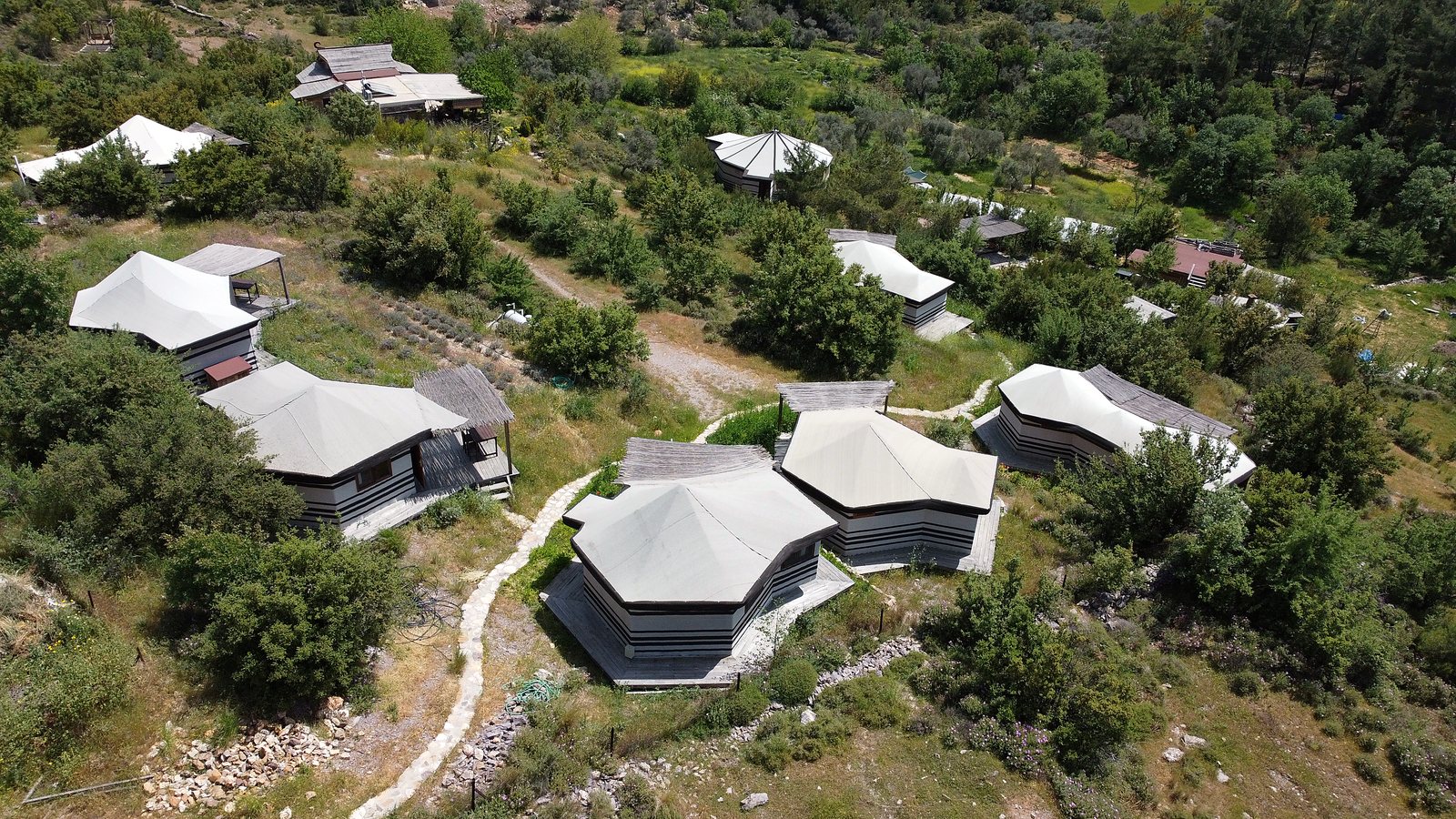 Aerial view of the retreat's tent-shala cabins scattered across the hillside